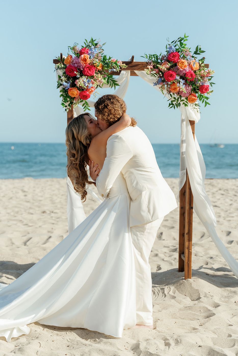 A couple beneath a floral arch on the beach